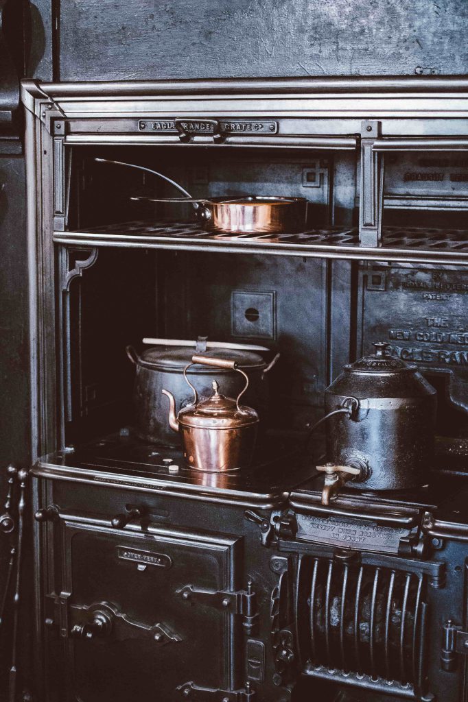 Une cuisinière à bois noire avec casseroles en cuivre