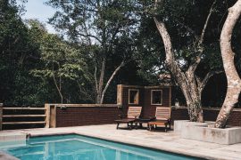 piscine extérieure avec terrasse en béton et transats en bois sous des arbres